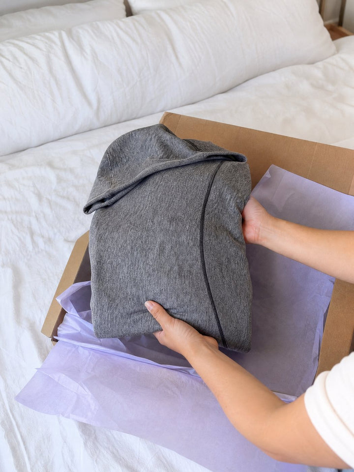 Unboxing a folded grey Snuggl Pod from lavender tissue paper
