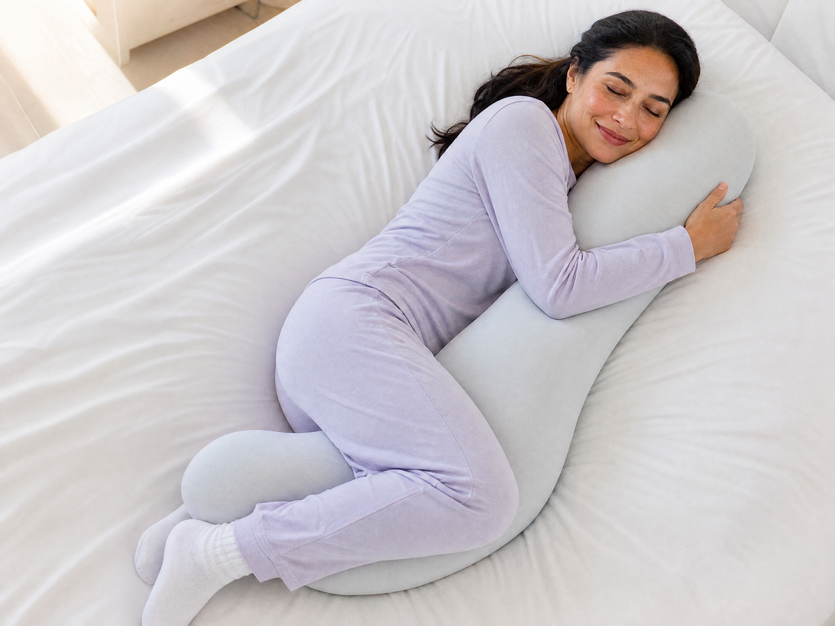 Woman side sleeping while hugging the Snuggl Body Pillow